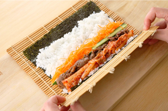 巻きすにのりをのせ、手前を幅1センチ、奥は幅2センチほどあけて、すし飯の1/4量を広げる。手前にキムチ、牛肉、にんじん、きゅうりをそれぞれ1/4量ずつのせる。ぎゅっと締めるように巻きつけ、形をととのえる。残りも同様に巻いて、食べやすい太さに切る。
