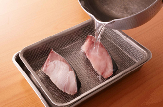 ぶりはざるにのせ、熱湯を回しかける。こうすると、くさみが取れて、余分な脂も落ちる。
