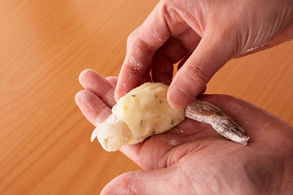 残りのポテト生地2個を使ってえびコロッケを作る。えびは尾と尾の近くの一節を残して殻と足を外し、尾の先を2～3ミリ切り落とし、こすって中の水分を出す。背わたがあれば竹串で取って塩、酒をもみこんで5分おく。さっと洗ってペーパータオルで水気を拭き、こしょうをふる。ポテト生地1 個を半分にし、えびの胴に巻きつけるようにして形をととのえる。同様にして、合計4個作る。