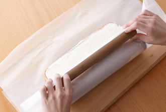 オーブン用シートごと手前を持ち上げ、向こう側に折りたたむ。端に麺棒を当て、均一に力を入れながら向こう側に転がす。巻き終えたら形をととのえ、オーブン用シートの左右をキャンディーのようにひねり、冷蔵庫で40分以上休ませてから食べましょう。