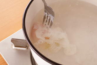 ポーチドエッグを作る。鍋に湯を3カップくらい沸かし、酢大さじ2を加える。弱めの中火にし、小さな器に割り入れた卵をそっと入れる。フォークなどで白身が散らないようにおさえながらゆで、白身が固まったら火を止め、ふたをして2～3分蒸らす。もう１個も同様にして作り、取り出して水気をきる。皿にアスパラガスを盛り、オリーブ油、塩少々、こしょう少々をふる。ポーチドエッグをのせ、削ったチーズとこしょうを散らす。
