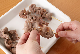 牛すじ、大根の下ごしらえをする。牛すじは鍋に入れ、かぶるくらいの水を入れて火にかけ、沸騰したらざるに上げて水気をきる。一口大に切り、竹串にぬうようにして刺す。大根は厚さ2センチの半月切りにする。