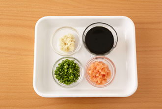 薬味とポン酢じょうゆを用意する。大根に菜箸で穴をあけ、種を除いた赤唐辛子を差し込み、一緒にすりおろしてもみじおろしにする。万能ねぎは小口切りにし、しょうがはすりおろす。