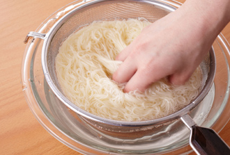 そうめんをゆでて冷水にとって洗い、ざるに上げて水気をきる。
