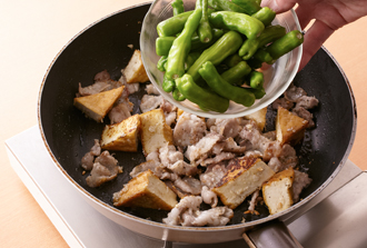 フライパンを中火で熱し、厚揚げを入れて全体を焼きつける。こんがりとしてきたら豚肉、にんにくを加えて炒める。肉の色がしっかりと変わってきたらサラダ油を入れ、しし唐辛子を加えてしんなりするまで炒める。
