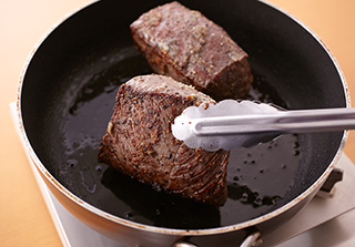 小さめのフライパン（または小鍋）にオリーブ油を弱めの中火で熱し、肉を並べ入れる。1つの面につき各1分30秒ずつ焼き、全体をこんがりと焼く。火を止めてコンロから外してふたをし、そのまま15分おく（牛肉を300ｇに切り分けられない場合は、火加減やおく時間は調整する）。