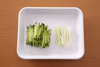 きゅうり、ねぎはそれぞれ長さ5～6センチの細切りにする。鶏肉は筋を切り、厚みのある部分に包丁を寝かせるようにして切り込みを入れ、厚みが均一になるように切り開く。