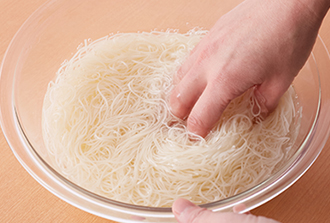 そうめんはたっぷりの湯（分量外）で表示時間ゆでて、冷水にとって洗い、ざるに上げて水気をよくきる。Bを加えてあえ、器に盛る。1のひき肉そぼろ、ねぎ、にら、削り節、卵黄をのせ、混ぜながら食べる。