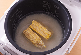 米をといで炊飯器に入れ、塩、みりんを入れてから通常の目盛りまで水（分量外）を加えて混ぜる。とうもろこしの芯をのせ、普通に炊く。