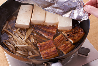 フライパンにごぼう、うなぎ、豆腐とAを入れ、アルミホイルで落としぶたをして中火にかけ、煮立ってから更に15分ほど煮て、火を止める。粗熱を取って味をなじませる。器に盛って三つ葉をのせ、粉山椒をふる。