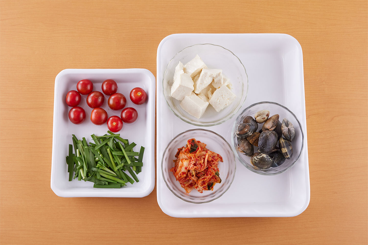 あさりは殻と殻をこすり合わせて洗い、水けをきる。豆腐は一口大にちぎる。ミニトマトはヘタを取る。にらは3cm長さに切る。白菜キムチは食べやすく切る。
