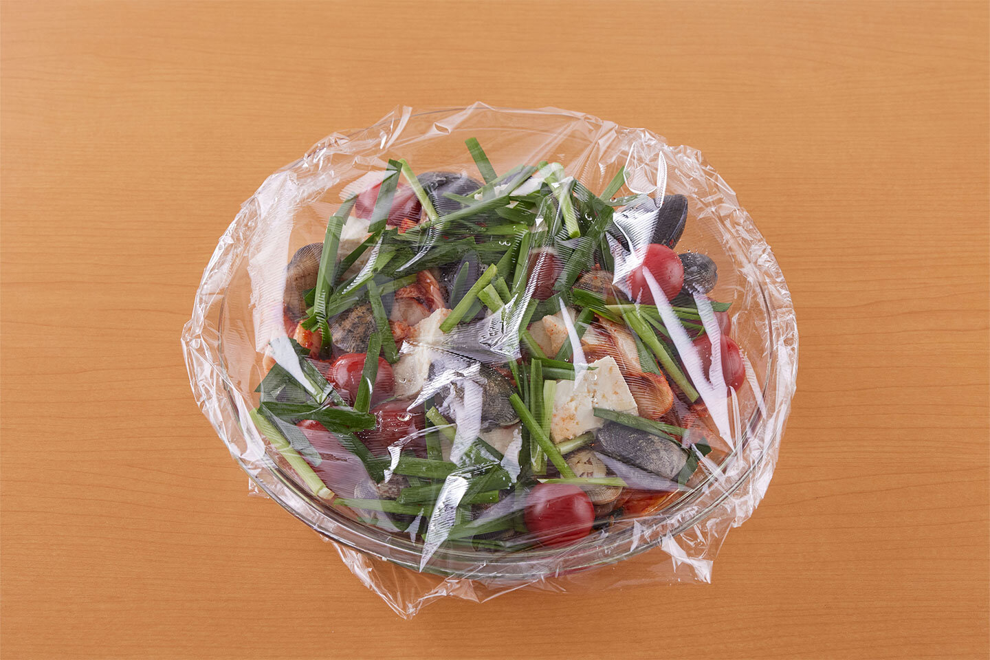 耐熱皿に豆腐、キムチ、あさりを広げて入れ、ミニトマト、にらを散らす。酒、ごま油をかけ、ラップをふんわりとかけ、電子レンジ（600W）で7〜8分加熱する。しょうゆをかけて混ぜ合わせ、器に盛る。