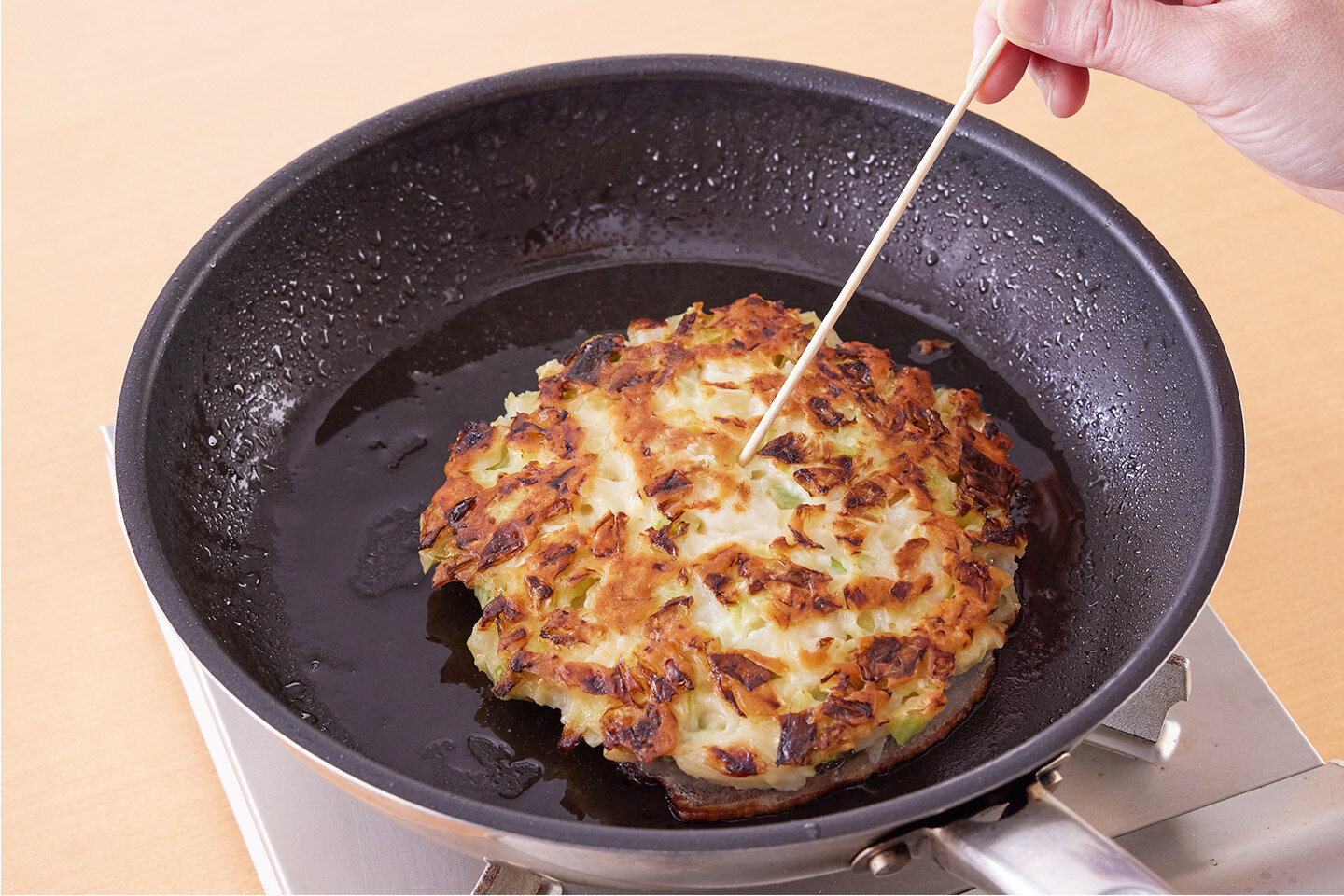 ふたを外して上下を返し、再びふたをして3分蒸し焼きにする。こんがり焼けたら、竹串で中央を刺してみて、生地がついてこなければ焼き上がり。<br>残りも同様に焼く。器に盛り、全体にソースを塗ってマヨネーズをかける。青のりを散らし、紅しょうがをのせる。